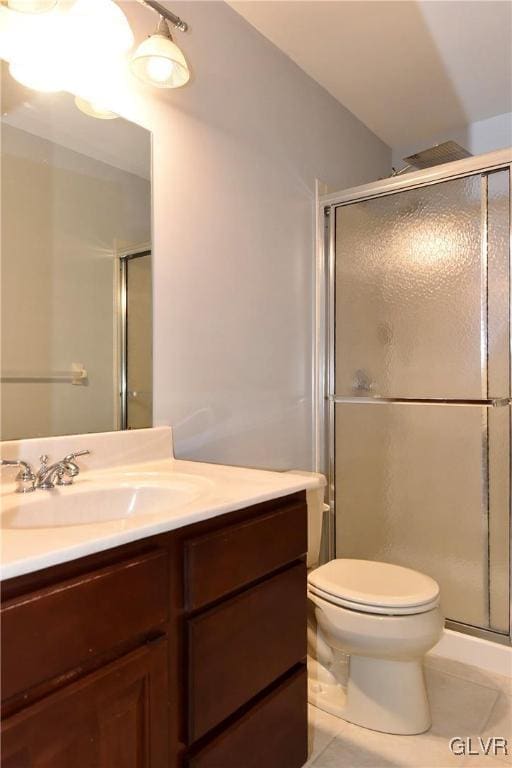 bathroom featuring toilet, a stall shower, vanity, and tile patterned floors