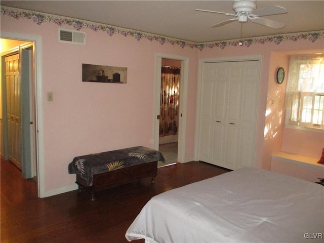 bedroom with baseboards, visible vents, wood finished floors, ensuite bathroom, and a closet