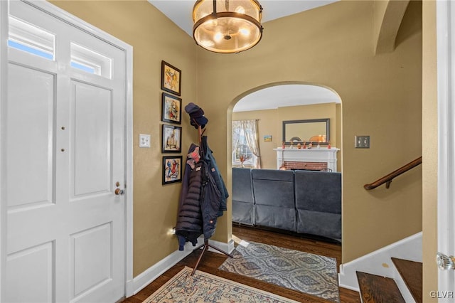 entryway featuring arched walkways, baseboards, and wood finished floors