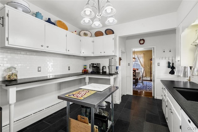 kitchen with white cabinetry, baseboard heating, backsplash, dishwasher, and dark countertops