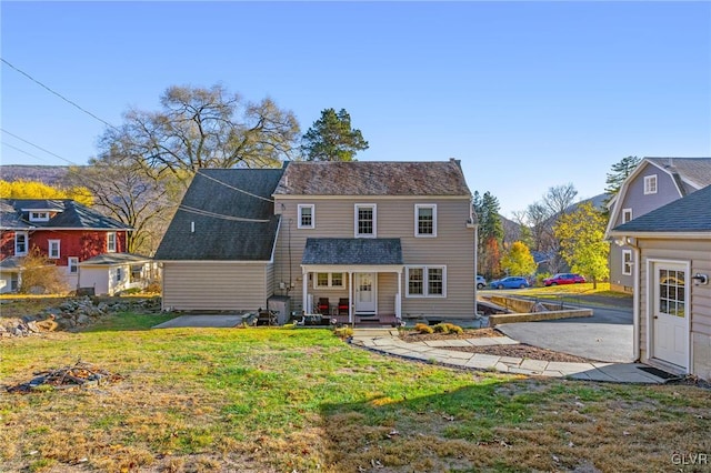 rear view of property with roof with shingles and a yard