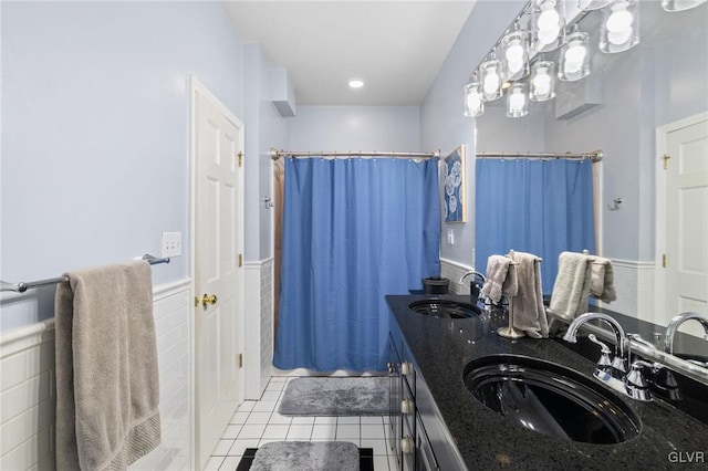 bathroom featuring a shower with curtain, tile patterned flooring, a sink, and wainscoting