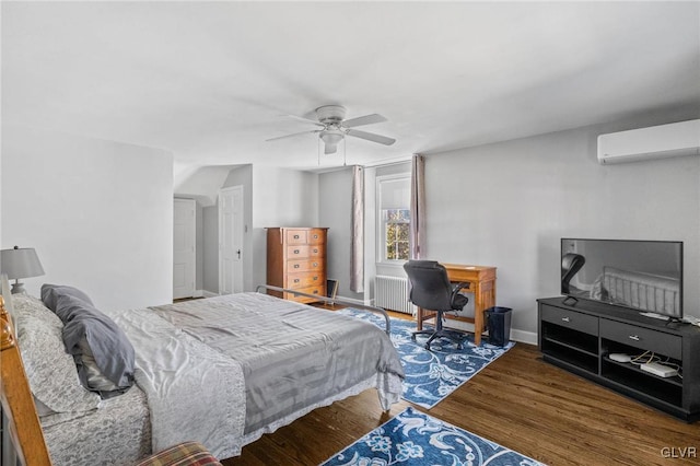 bedroom featuring ceiling fan, wood finished floors, baseboards, radiator, and a wall mounted air conditioner