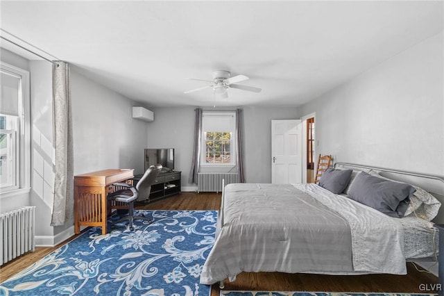 bedroom with radiator, baseboards, wood finished floors, and a wall mounted air conditioner