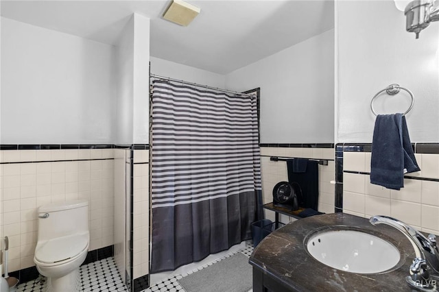 bathroom featuring curtained shower, a wainscoted wall, tile walls, and toilet