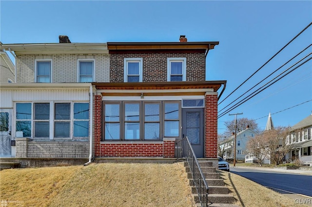 multi unit property with a front yard, brick siding, and a chimney