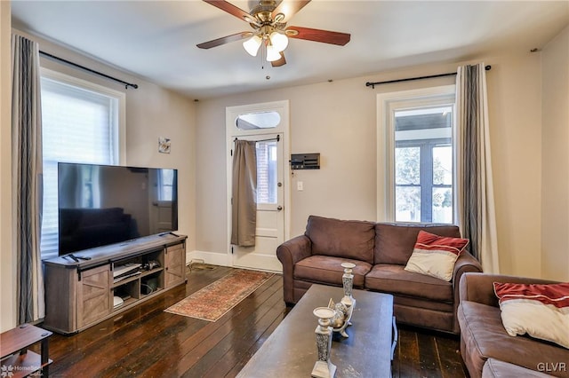 living room featuring ceiling fan, baseboards, and dark wood finished floors