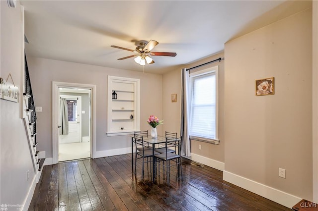 dining room featuring ceiling fan, visible vents, baseboards, and dark wood finished floors