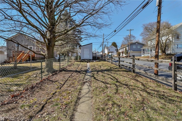 view of yard with a residential view, fence, an outdoor structure, and a storage unit