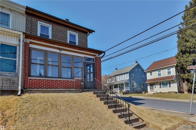 view of front of property with brick siding, a front lawn, and a residential view