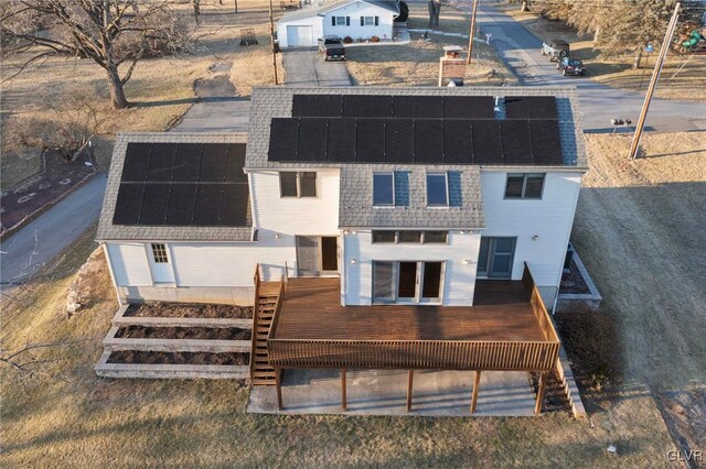 back of property featuring stairway, roof mounted solar panels, roof with shingles, and a deck