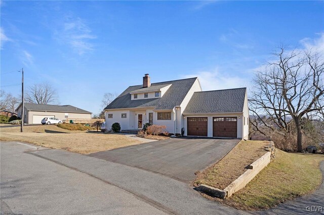 view of front of property with roof with shingles, aphalt driveway, a chimney, and an attached garage