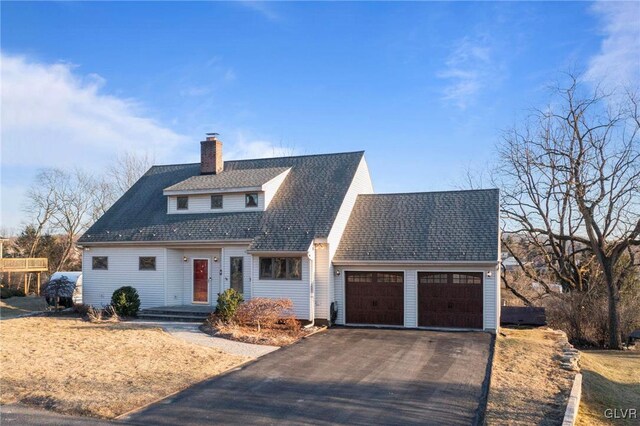 view of front of home featuring a garage, a shingled roof, a chimney, and aphalt driveway