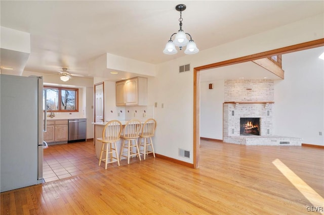 kitchen featuring stainless steel appliances, a kitchen bar, visible vents, and light wood-style floors