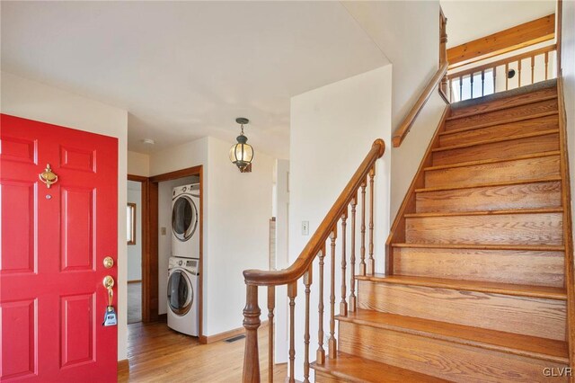 entrance foyer featuring light wood-type flooring, stacked washing maching and dryer, and stairway