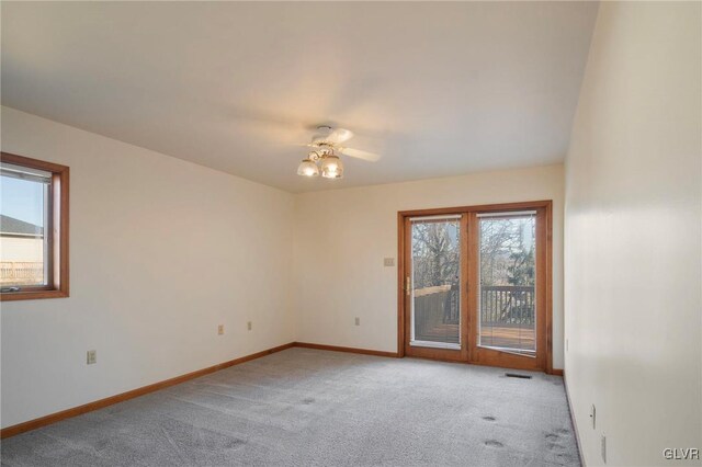 unfurnished room featuring baseboards, visible vents, a ceiling fan, and light colored carpet