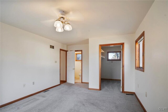 unfurnished bedroom featuring carpet floors, visible vents, a spacious closet, and baseboards