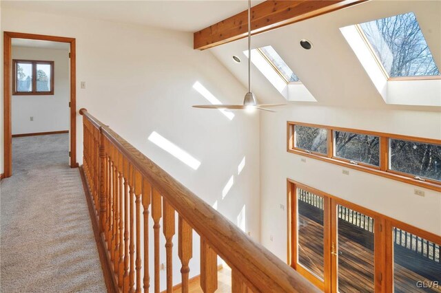 hall with carpet floors, a skylight, an upstairs landing, high vaulted ceiling, and beamed ceiling