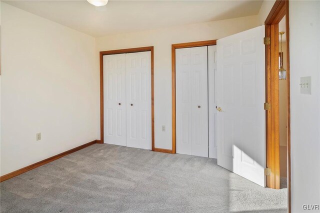 unfurnished bedroom with carpet, baseboards, and multiple closets