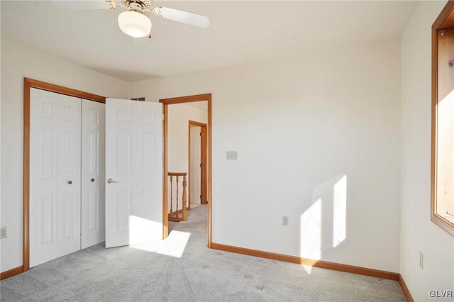 unfurnished bedroom with a closet, light colored carpet, and baseboards