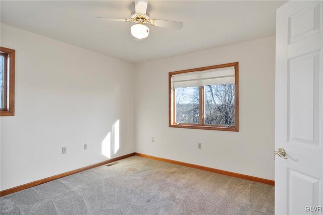 carpeted spare room with a ceiling fan, visible vents, and baseboards