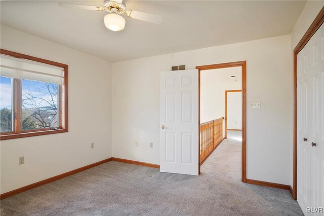 empty room with light carpet, visible vents, baseboards, and ceiling fan