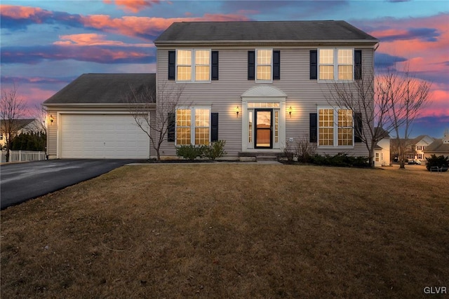 colonial inspired home with a garage, aphalt driveway, and a front yard