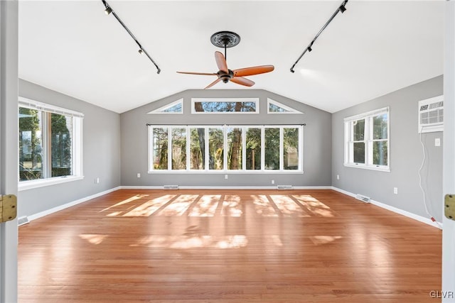 interior space with a wealth of natural light, visible vents, an AC wall unit, and wood finished floors