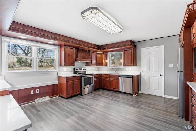 kitchen featuring stainless steel appliances, light countertops, custom range hood, visible vents, and a sink