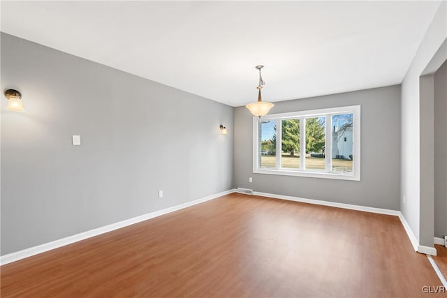 unfurnished room with visible vents, baseboards, and wood finished floors