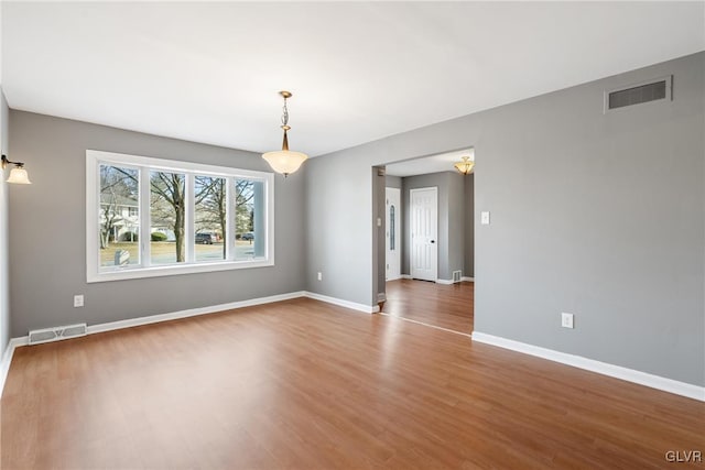 empty room featuring baseboards, visible vents, and wood finished floors