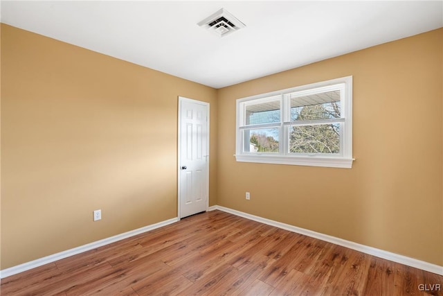 spare room with visible vents, baseboards, and wood finished floors