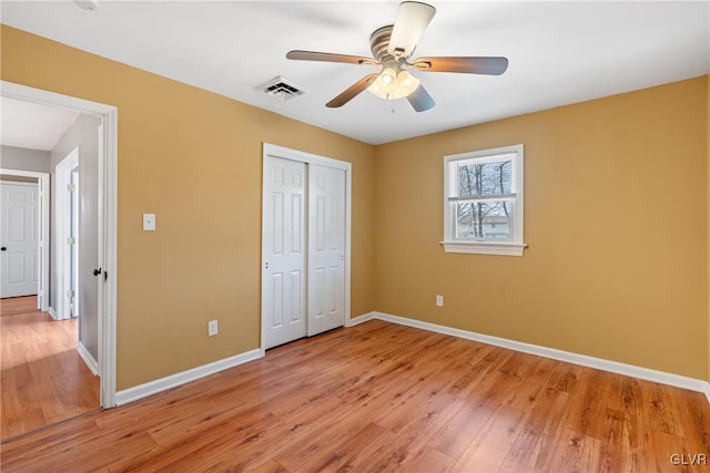 unfurnished bedroom with light wood finished floors, baseboards, visible vents, and a closet