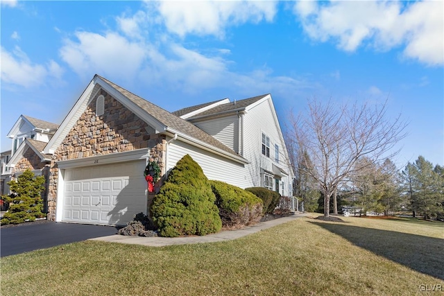 view of side of home featuring a garage, stone siding, aphalt driveway, and a lawn