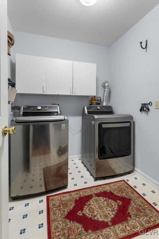 laundry room featuring baseboards, cabinet space, independent washer and dryer, and light floors