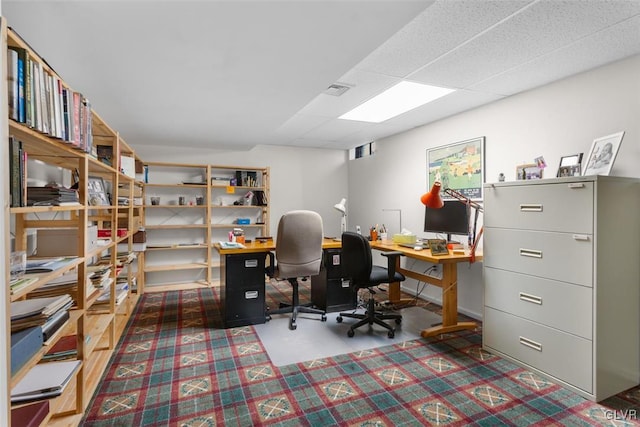 home office with concrete flooring, a paneled ceiling, and visible vents