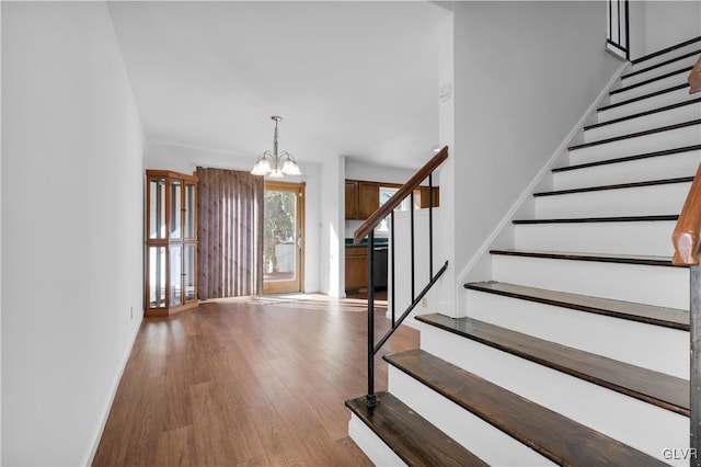 stairs with baseboards, an inviting chandelier, and wood finished floors