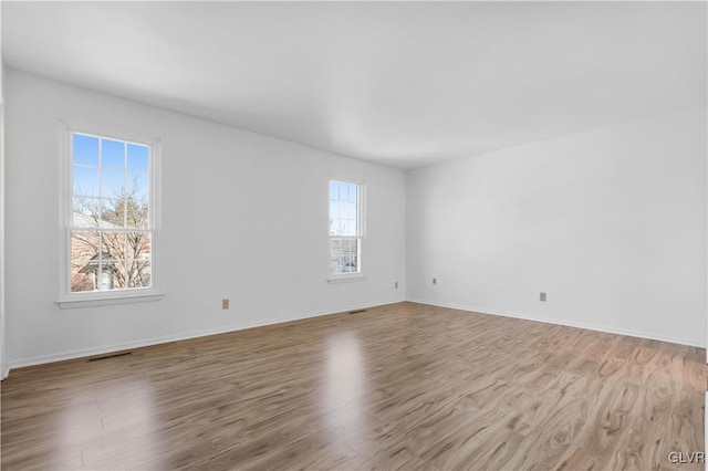 empty room with visible vents, baseboards, and wood finished floors