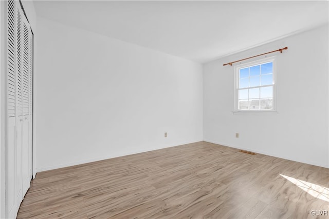 empty room with light wood-style flooring and visible vents