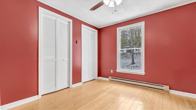 115 Aspen Cir E, Stroudsburg, PA 18302 - unfurnished bedroom with baseboard heating, multiple closets, wood finished floors, crown molding, and baseboards