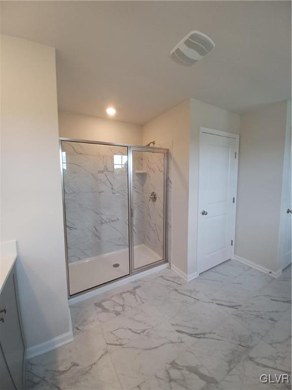 bathroom with marble finish floor, a marble finish shower, visible vents, and baseboards