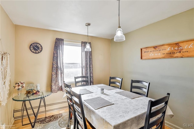 dining area featuring baseboard heating, wood finished floors, and baseboards