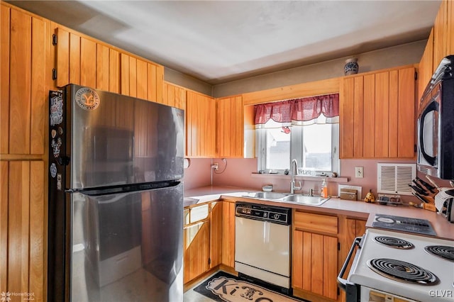 kitchen with light countertops, white appliances, and a sink