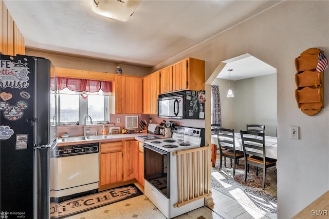 kitchen featuring arched walkways, light floors, light countertops, black appliances, and a sink