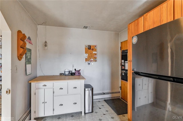 kitchen featuring light floors, a baseboard radiator, light countertops, freestanding refrigerator, and white cabinetry