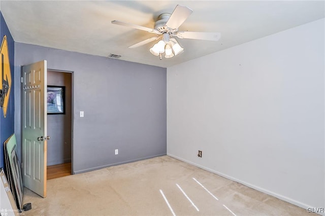 carpeted empty room featuring ceiling fan, visible vents, and baseboards