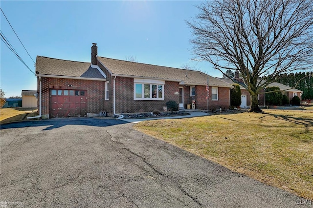 single story home with brick siding, a chimney, an attached garage, a front yard, and driveway