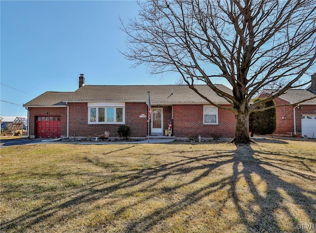 ranch-style home featuring a garage, driveway, brick siding, a chimney, and a front yard