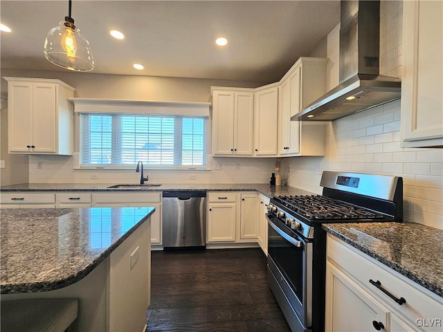 kitchen with wall chimney range hood, appliances with stainless steel finishes, white cabinets, and a sink