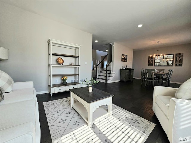 living area with recessed lighting, baseboards, stairs, dark wood-style floors, and an inviting chandelier